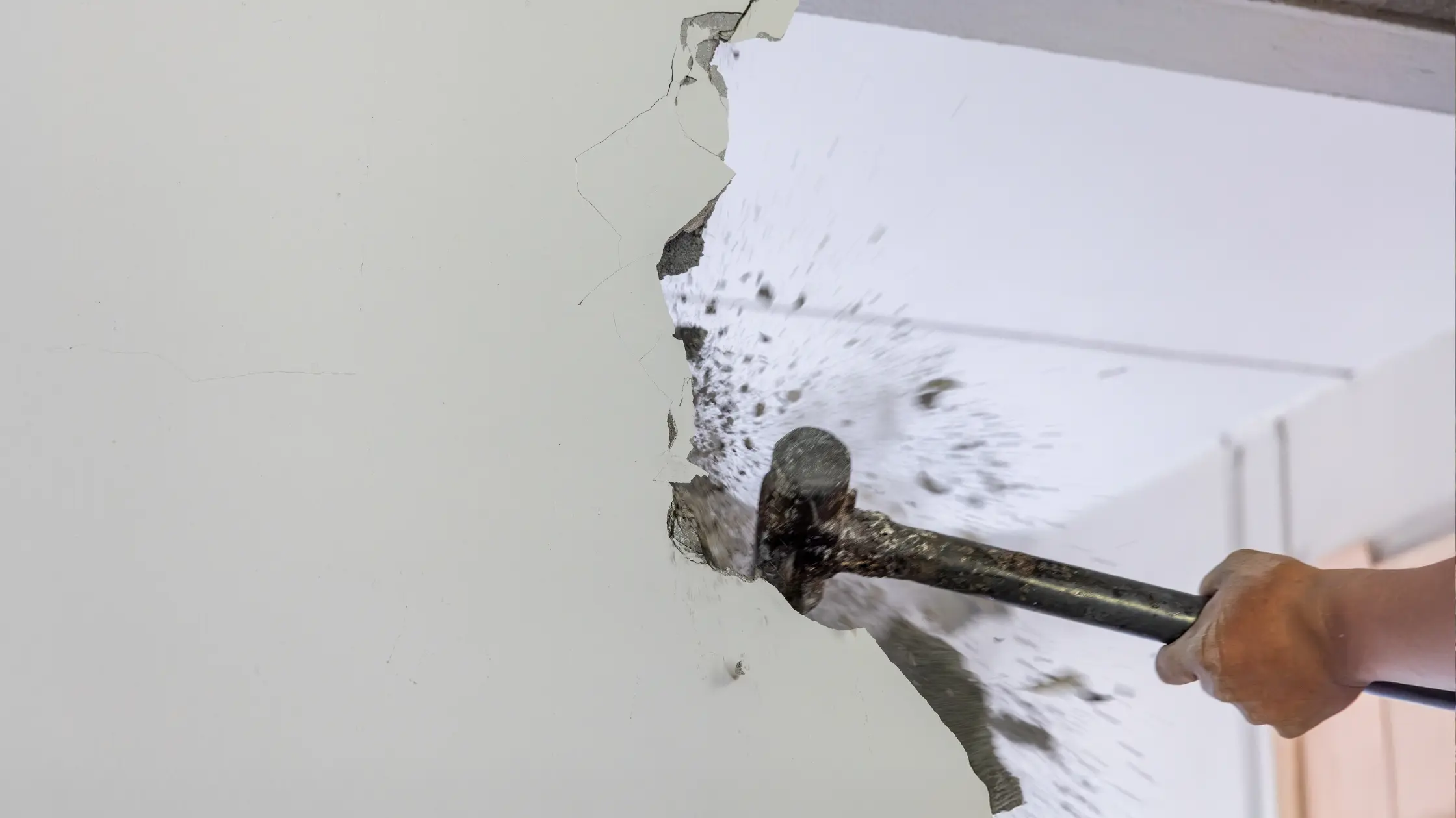 Démolition d'une cloison par un artisan avec une masse